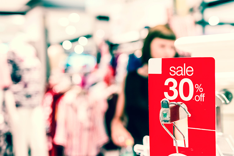 Un cartel rojo del 30% de descuento puesto en un burro de ropa en una tienda.